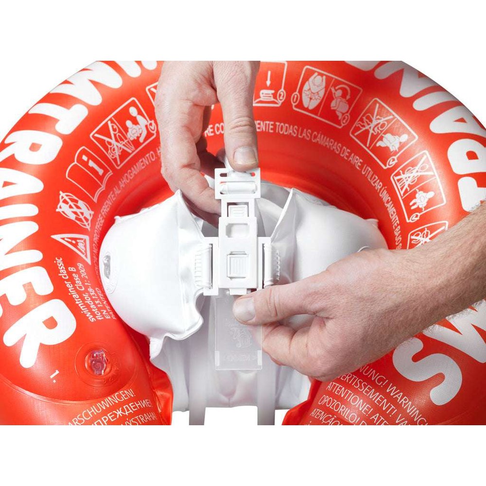 Freds Swimtrainer Classic Red infant swim trainer with white safety clip, for ages 3M–4Y.