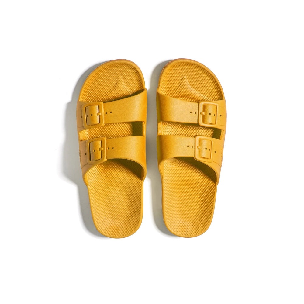 Freedom Moses Prints Adult Mikado yellow sandals with two adjustable buckle straps laid flat.