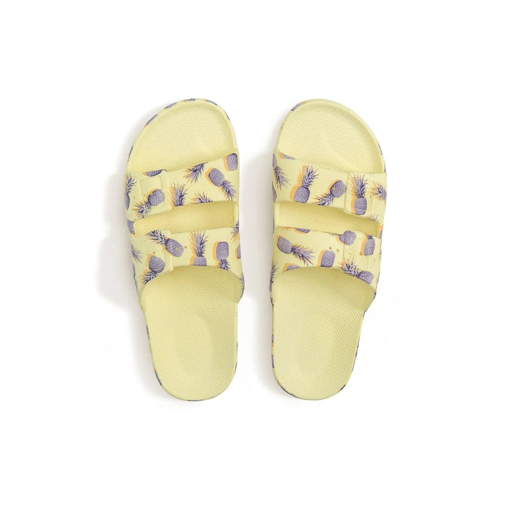 Freedom Moses Prints Pina Colada Sugar slides in sunny yellow with pineapple print, featuring two adjustable straps.