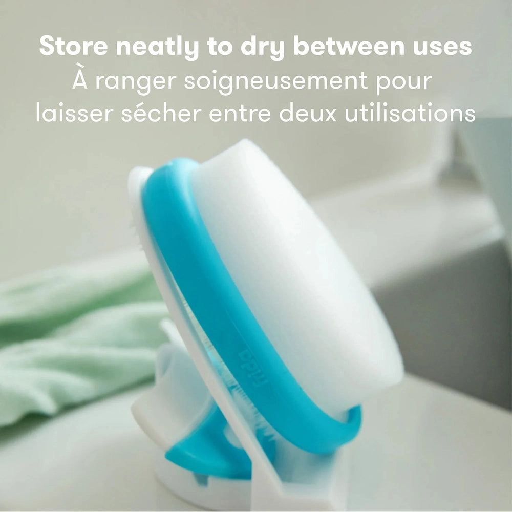 Frida Baby Dermafrida The Flakefixer baby skincare tool with blue grip and white head by FRIDA