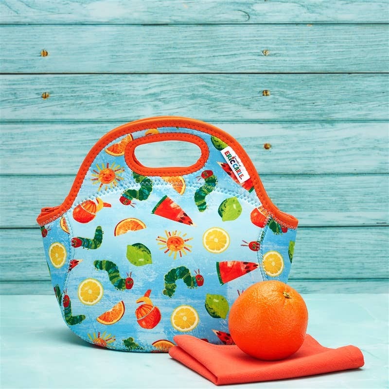 Blue insulated lunch bag with orange trim and handle, citrus fruit print; orange fruit and napkin placed beside.