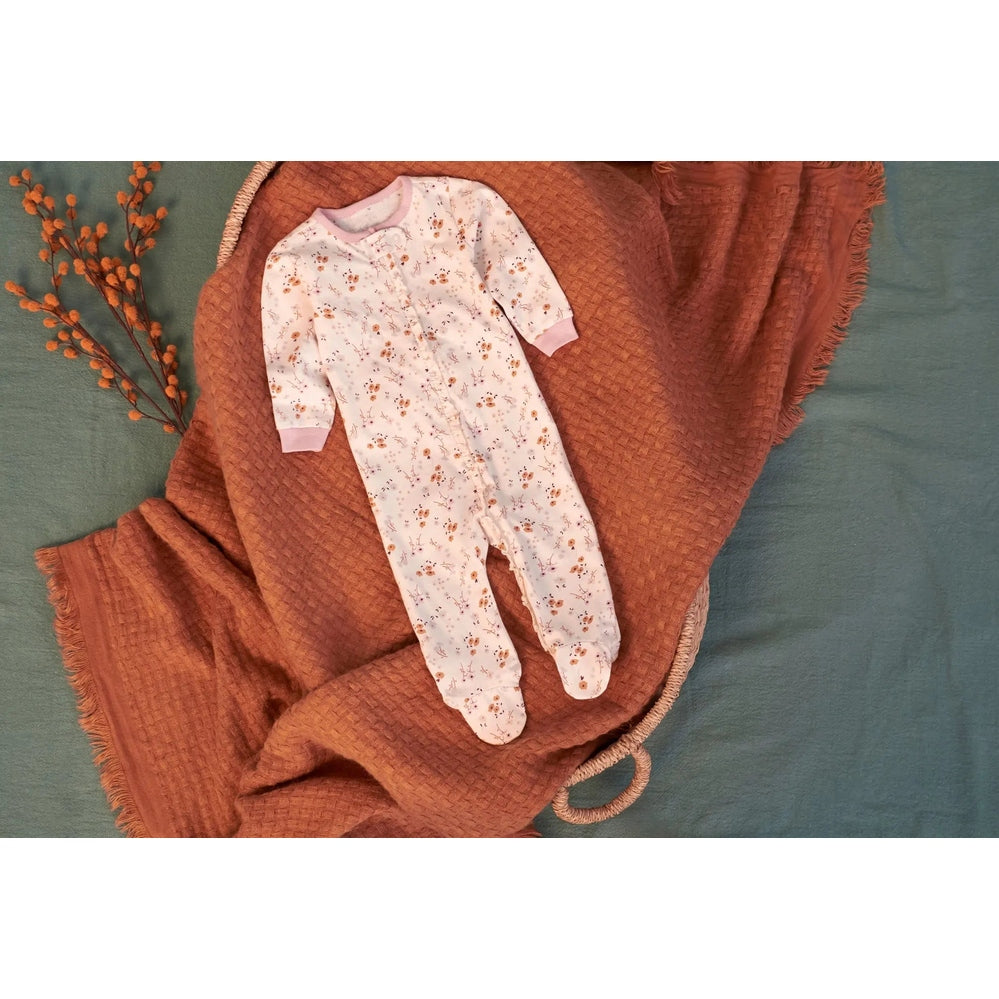 Gerber Baby Boys Floral Sleep 'N Play in white with orange-brown flowers, laid flat on a rust textured blanket.