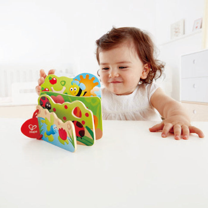 Hape Baby's Bug Book wooden toy where a toddler flips colorfully illustrated insect pages.