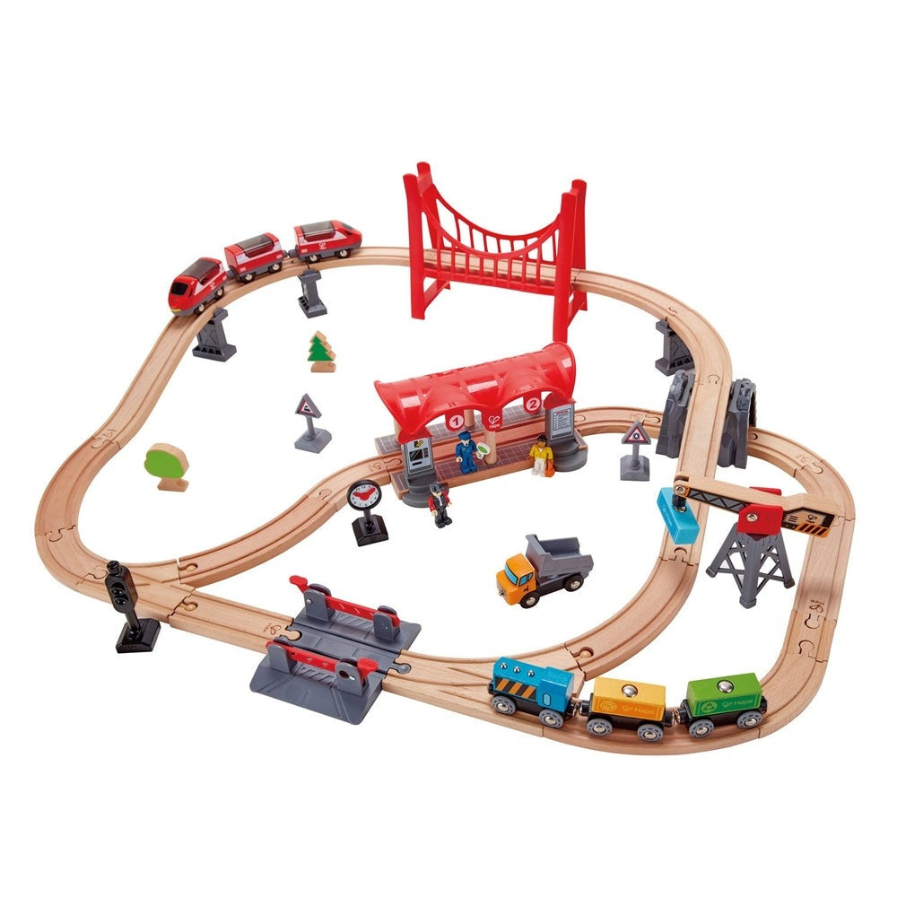 Hape Busy City Rail Set wooden train set with a red bridge; trains run along curved tracks past a station and figures