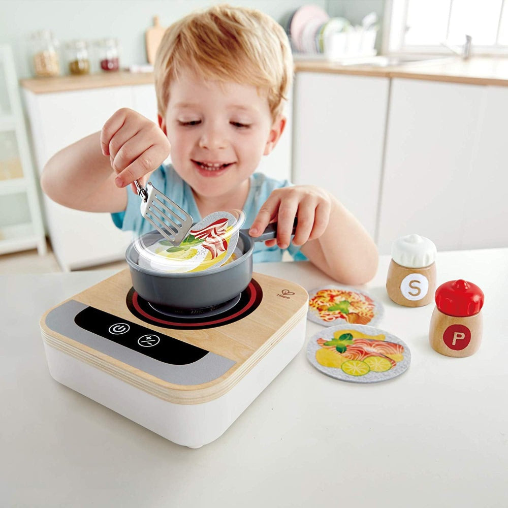 Hape Fun Fan Fryer toy kitchen appliance; child plays with pan, spatula, and colorful food discs.