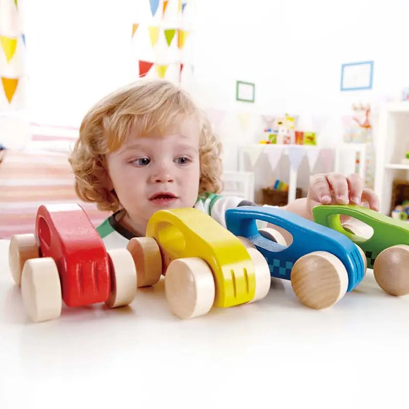 Hape Little Auto wooden toy cars in red, yellow, blue, green; child lines them up and plays.