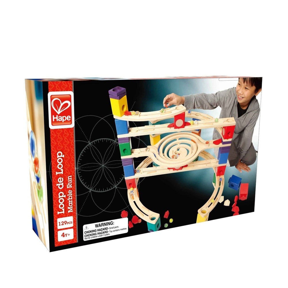 Hape Loop De Loop marble run toy in natural wood with colorful blocks; boy drops a marble down the spiraling track.