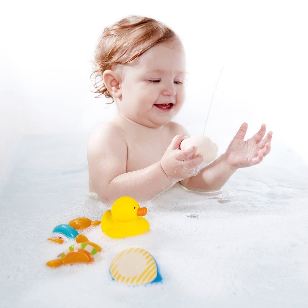 Hape Pallina Ocean Rescue bath toy set: a baby splashes with yellow duck and floating sea shapes during bath.