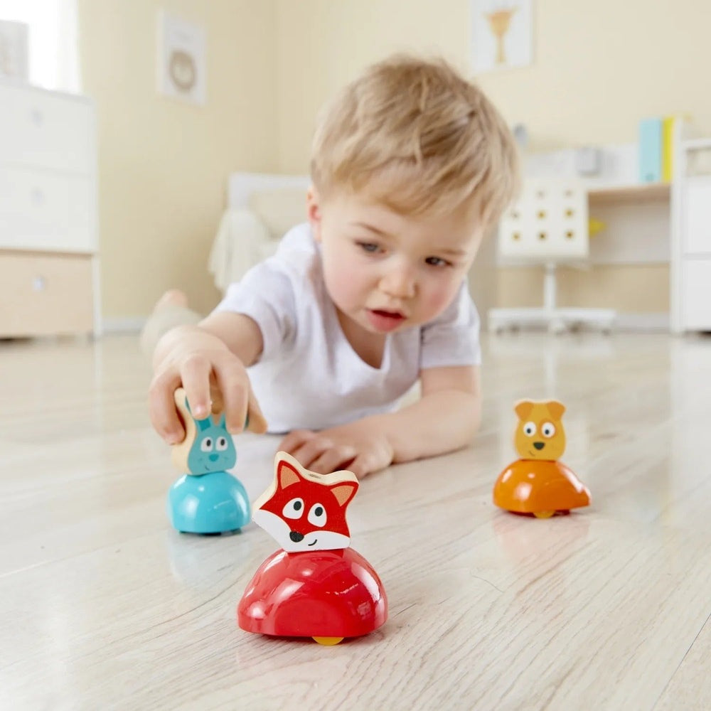 Hape Push & Run Bunny: a toddler pushes bright bunny figures along the floor, promoting motor play.