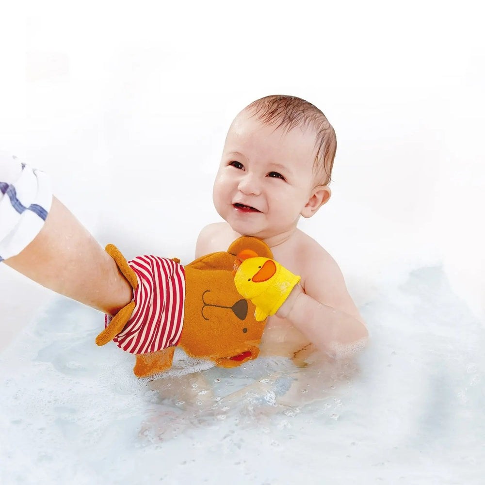 Hape Teddy And Duck Bath Mitt Set: baby in bath playing with orange bear mitt and yellow duck mitts.