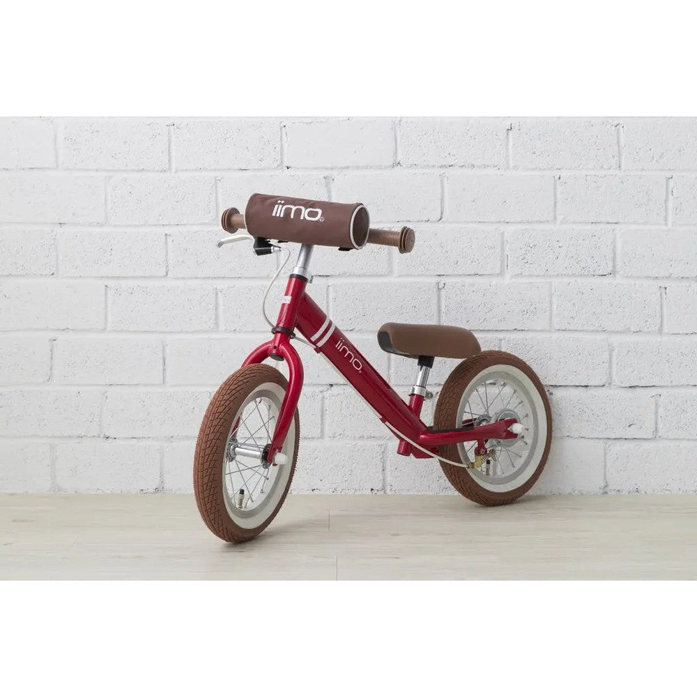 Iimo Balance Bike in red with brown saddle and grips, ready to ride on a light wood floor.