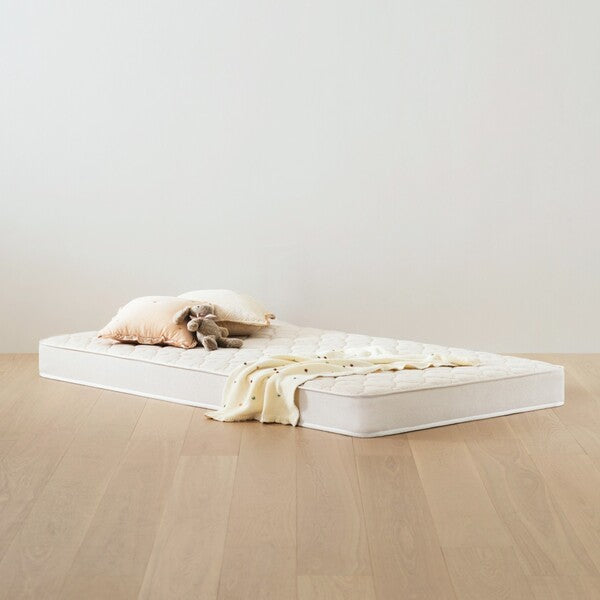 Iloom Daily Kids Mattress 1100W on wooden floor with cream blanket and plush toy