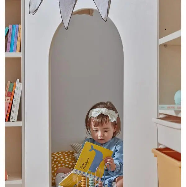 Iloom Eddi Kids Reading House corner unit with white arch doorway and curtain; a child sits inside reading a yellow book.