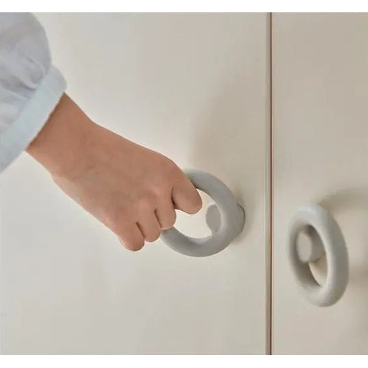 Iloom Eddi Kids Wardrobe door in white with a gray circular handle being gripped by a hand.