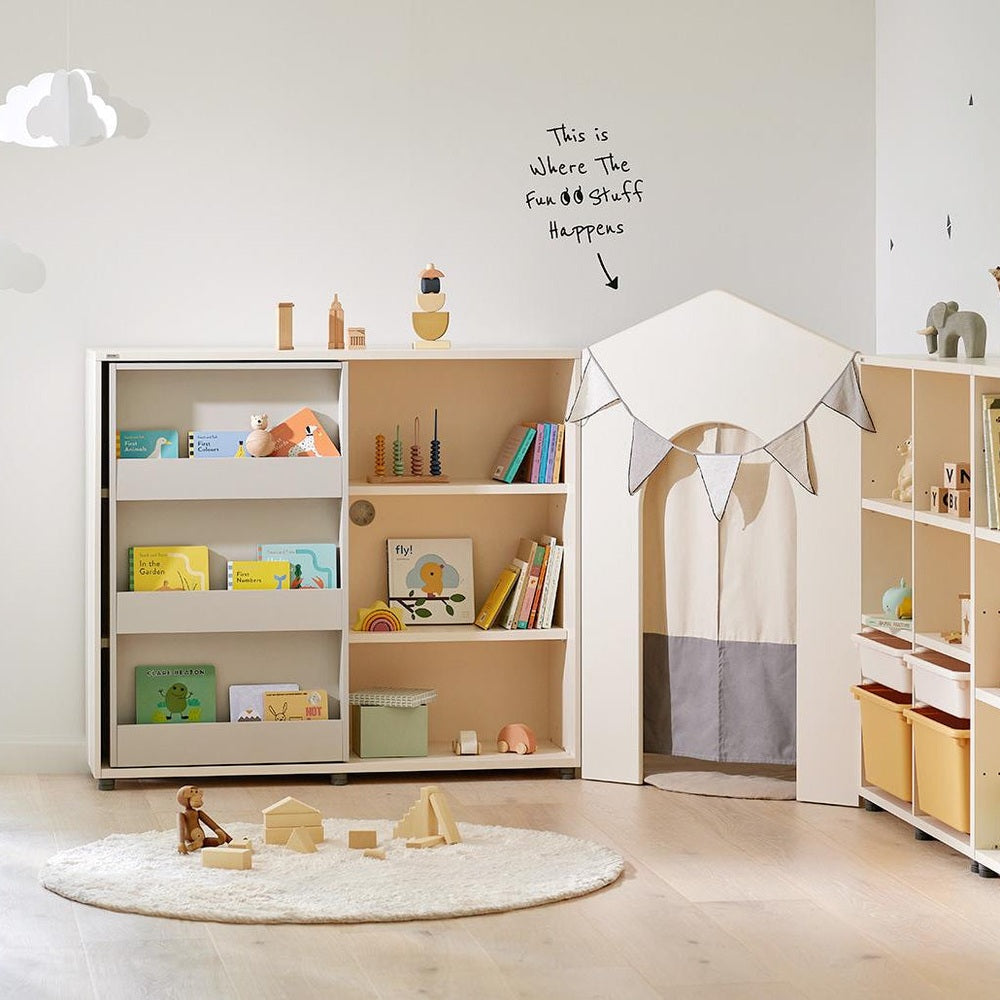 Iloom Eddie Kids Sliding Bookshelf, white frame with beige interior, showing colorful children's books and small toys.