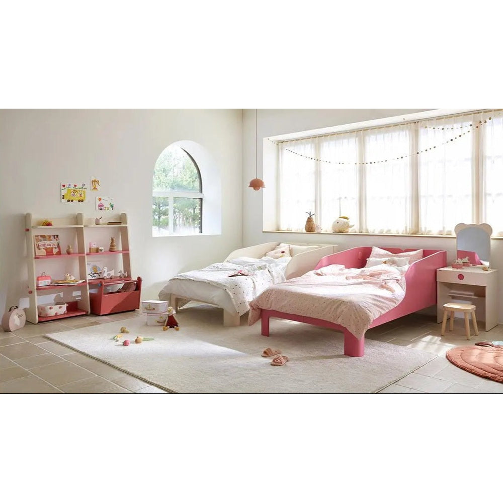 Iloom Tinkle Pop 1-Story Bed, pink toddler bed, shown in a bright nursery with soft bedding and a nearby white twin bed.