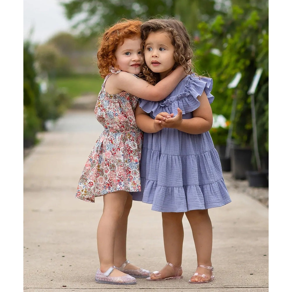 Isobella And Chloe Perry Pretty Cotton Gauze Dress Purple; girl in lavender-tiered, flutter-sleeve dress hugs a friend outdoors.