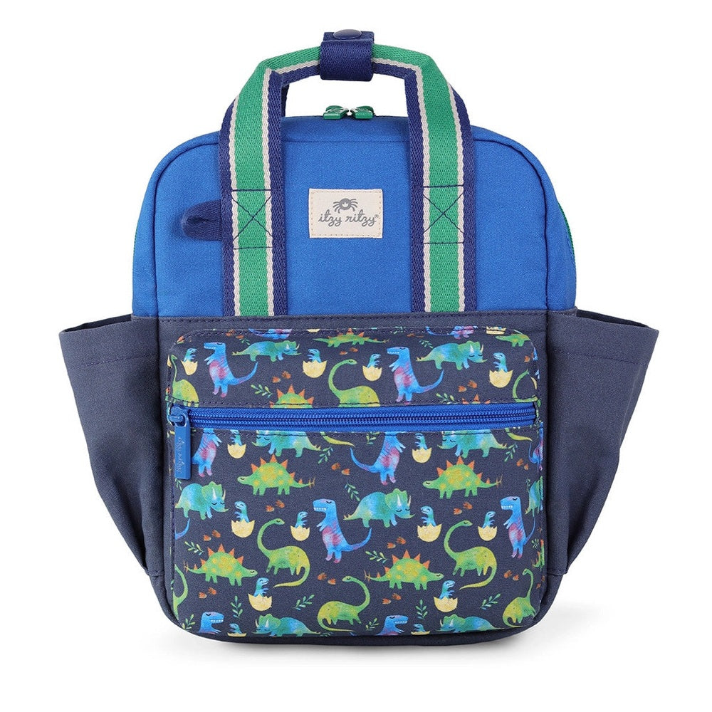 Itzy Ritzy Backpack, blue body with dinosaur-print front pocket; green striped straps ready to carry.
