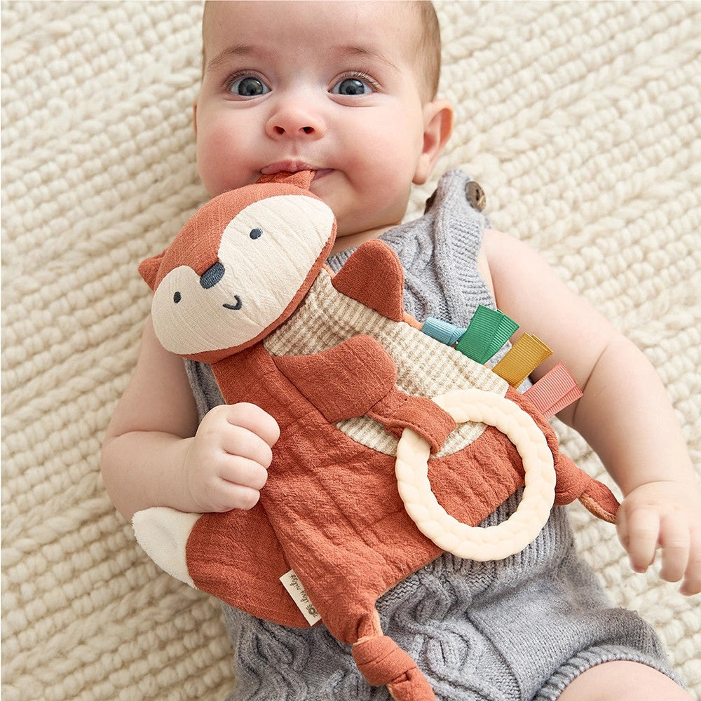 Itzy Ritzy Bitzy Crinkle Sensory Toy with Teether; orange fox plush, cream ring, and colorful tabs.
