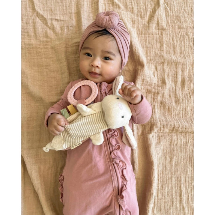 Itzy Ritzy Bitzy Crinkle sensory toy with teether, plush bunny held by baby in pink.