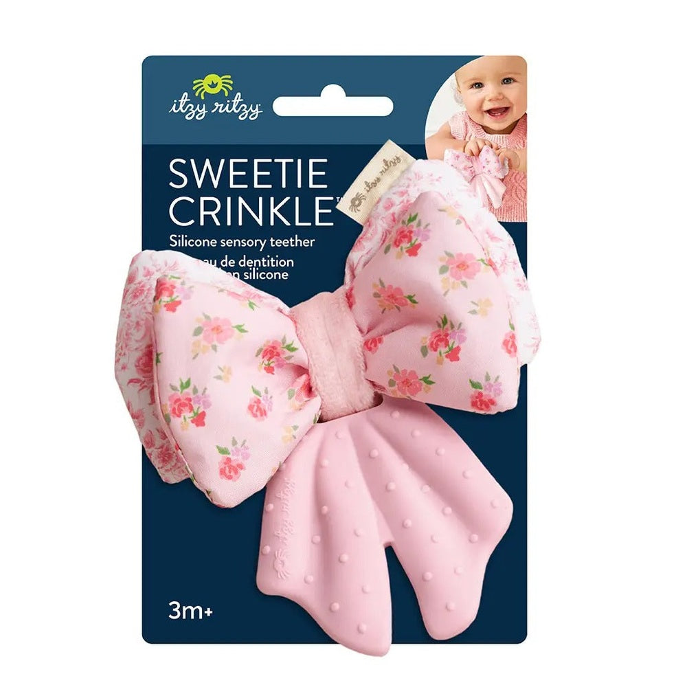 Itzy Ritzy Sweetie Crinkle silicone sensory teether in a pink floral bow, displayed on dark packaging.