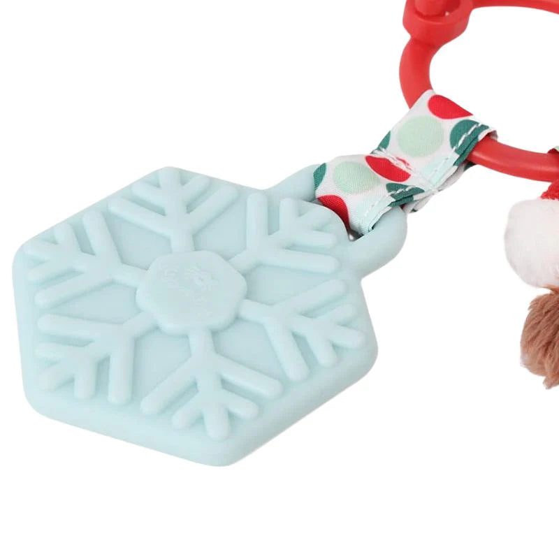 Itzy Ritzy Itzy Pal Plush Teether, pale blue snowflake silicone teether clipped to a red ring with a festive fabric bow.
