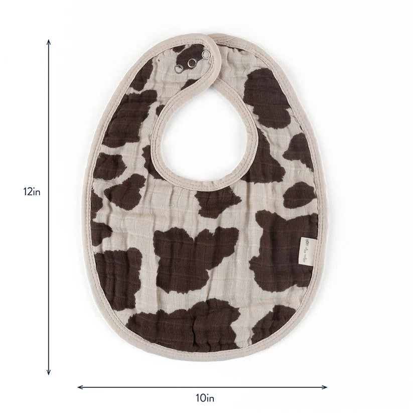 Itzy Ritzy Itzy Bibs cow-print baby bib with beige trim, snapped at neck, 12x10 inches