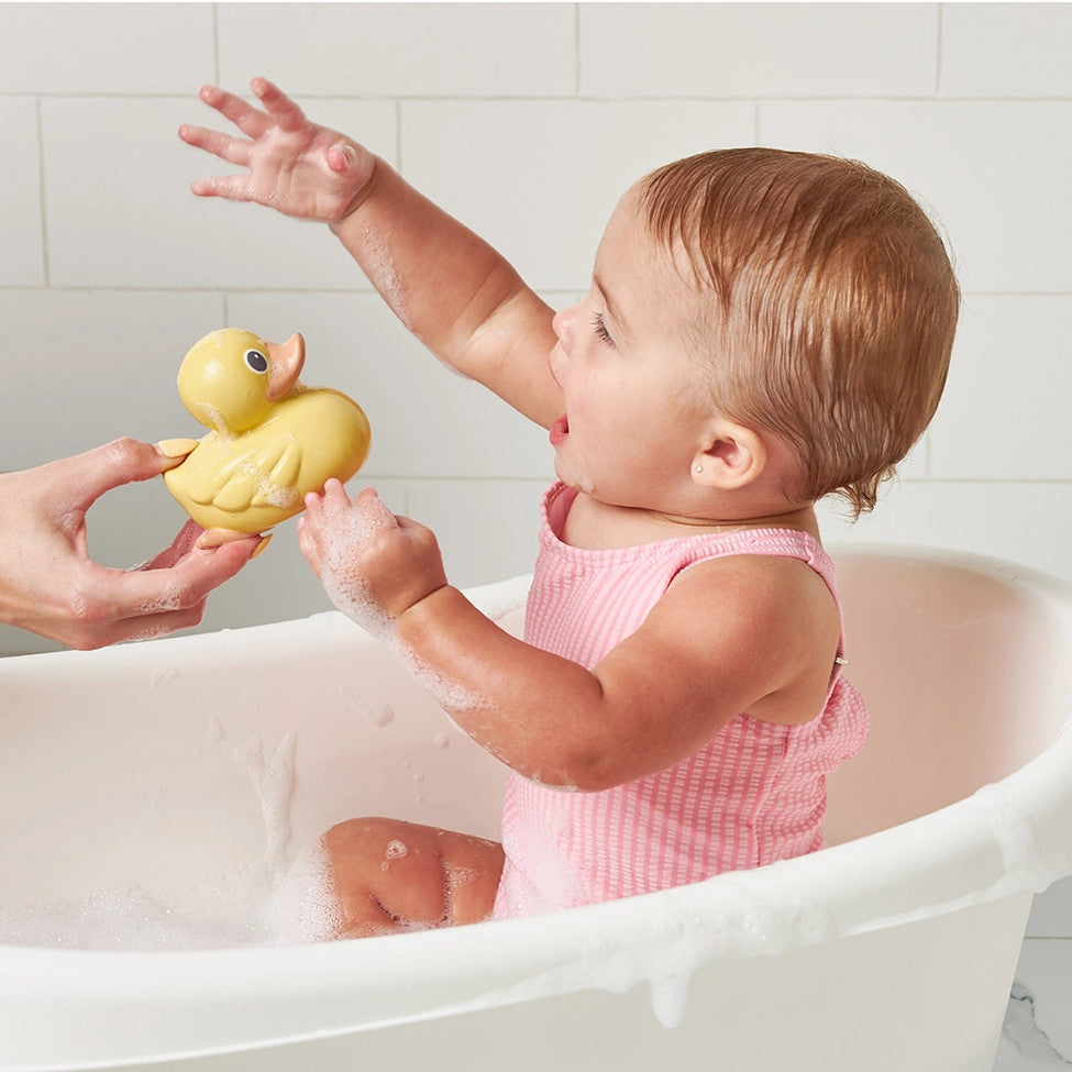 Itzy Ritzy Itzy Ducky Family bath toy; yellow rubber duck beside a baby in a white tub