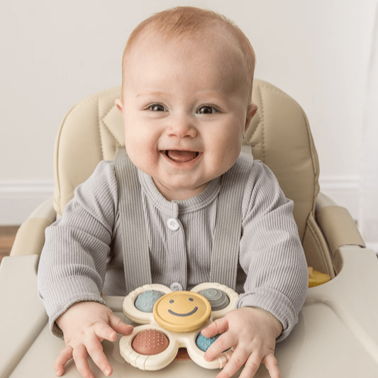 Itzy Ritzy Itzy Pop & Whirl baby toy in high chair; colorful spinning discs with a smiley face.