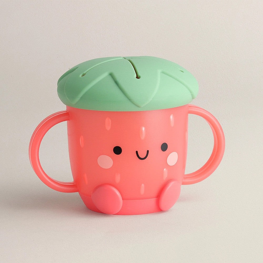 Itzy Ritzy Itzy Snack Cup, pink cup with a green leaf lid and dual handles, smiling toddler-friendly design