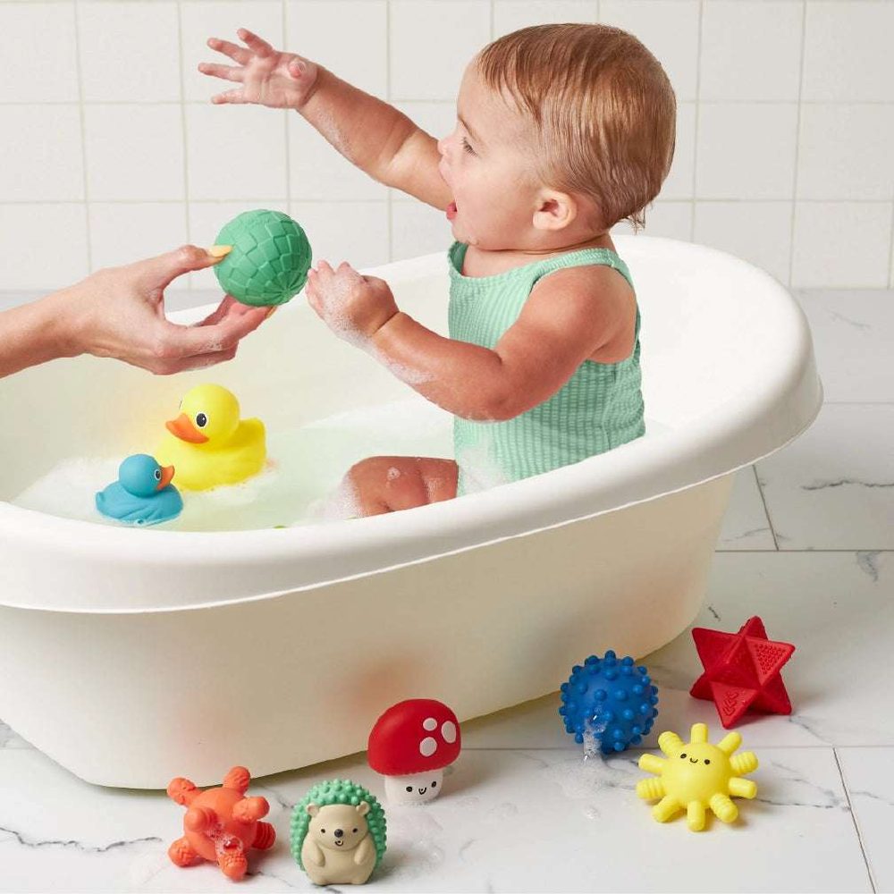 Itzy Ritzy Itzy Splash Bath Toys Gift Set with colorful ducks and textured balls around a baby in a bathtub