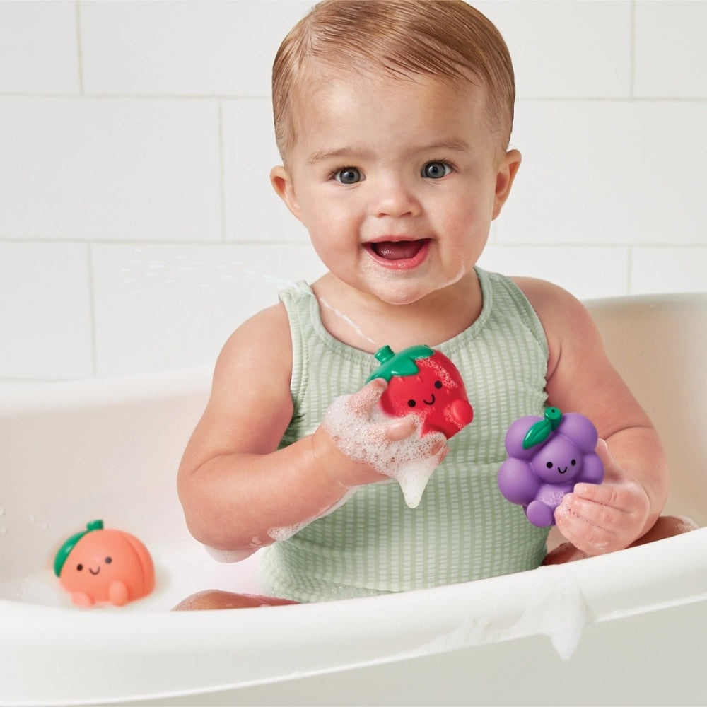 Itzy Splash Pals bath toys: red strawberry and purple grape held by smiling baby in bath