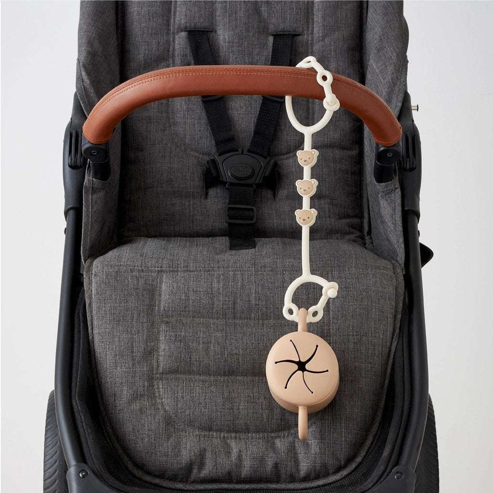 Itzy Ritzy Itzy Strap teething toy with beige chain and bear charms on gray stroller handle