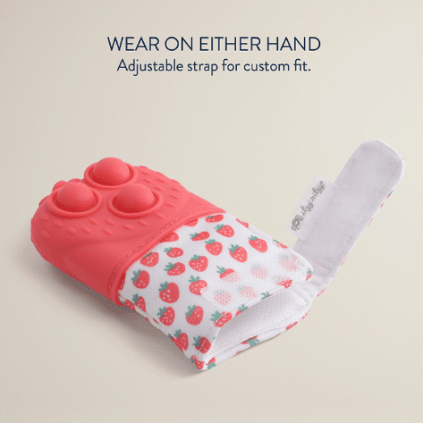 Itzy Ritzy Mitt Pop teething mitten; pink silicone exterior with strawberry-pattern fabric sleeve shown to highlight soothing grip.