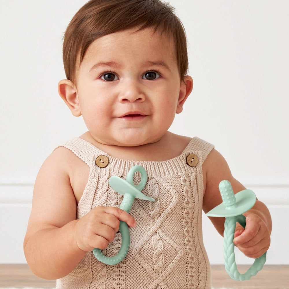 Itzy Ritzy Pre-Feeding Teether Set; mint green silicone teethers, 2-piece set held by a baby.