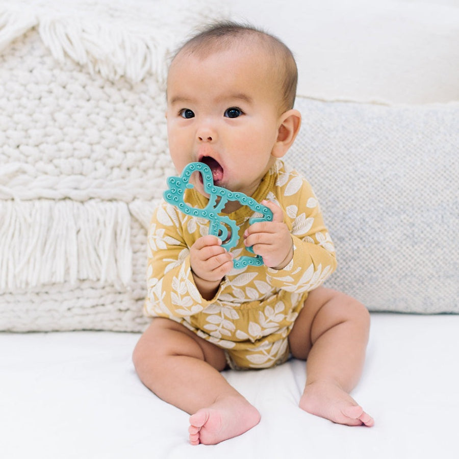 Teething toy Itzy Ritzy silicone teether in teal llama shape held by baby