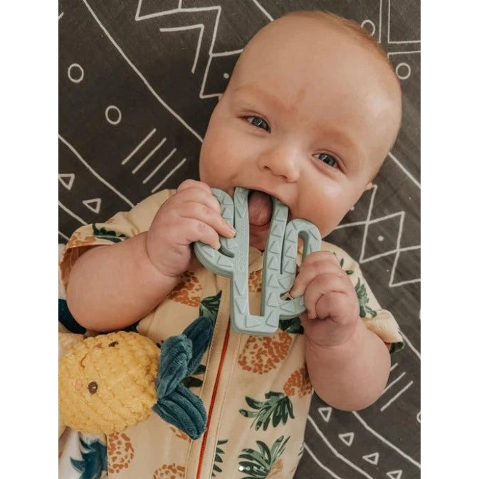 Itzy Ritzy teething mitten and teether gift set; mint teal silicone teether held by baby.