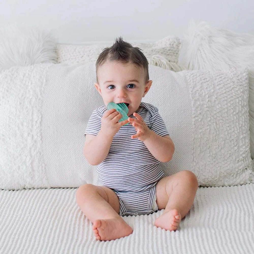 Itzy Ritzy Water-Filled Teethers 3pcs; baby chewing teal teether on white couch.