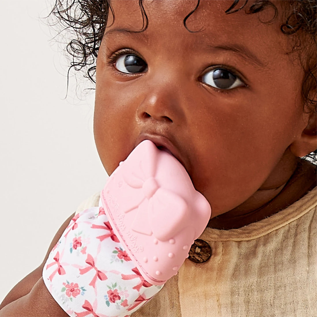 Baby using the pink Itzy Ritzy Itzy Mitt Bow teething mitten
