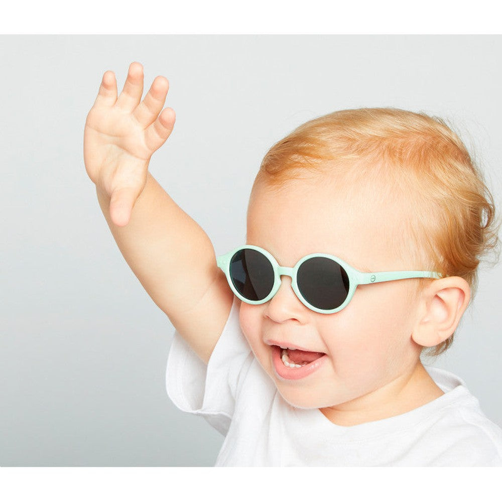 IZIPIZI Kids Sky Blue sunglasses with round black lenses on a smiling baby