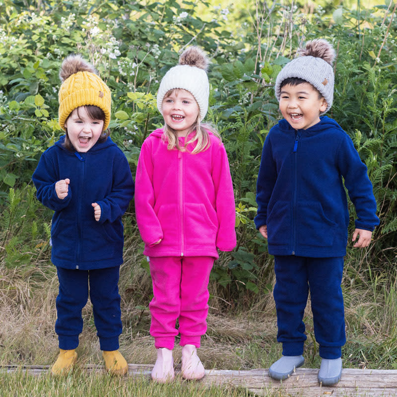 JAN & JUL Cable Knit Twinning Beanies set in mustard, white and grey worn by three kids outdoors.