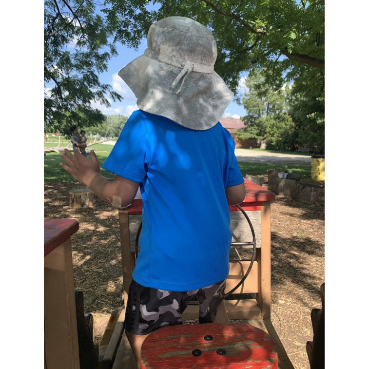 Jan & Jul Cotton Adventure Hats Black Tie-Dye worn by a child outdoors, wide brim shielding their face as they explore.