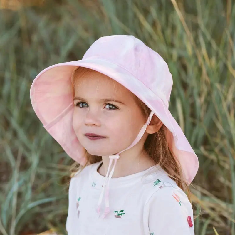 JAN & JUL Cotton Adventure Hats Prairie Flowers pink wide-brim toddler hat with chin strap, worn by a girl outdoors