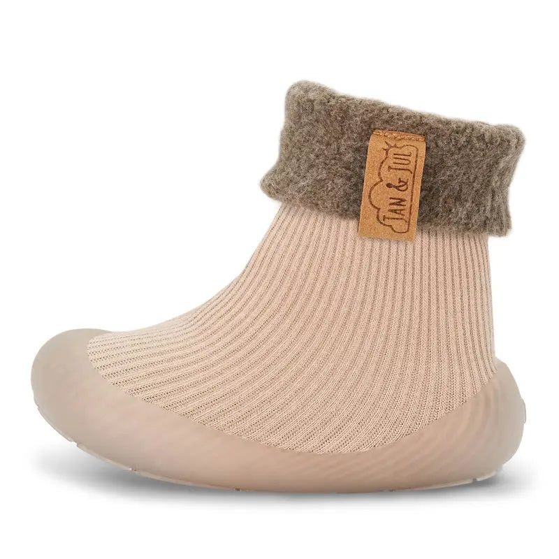 Jan & Jul Cozy Sock Shoes Oat on a toddler foot, beige knitted upper with grey cuff and soft rubber sole
