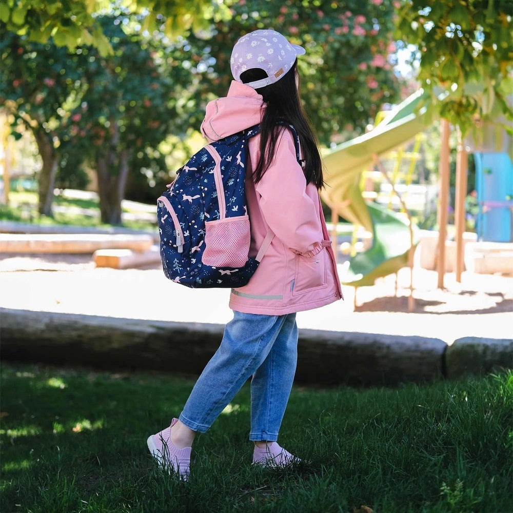 Jan & Jul kids backpack navy with pink mesh pocket and animal print, worn by child walking in a sunny park.