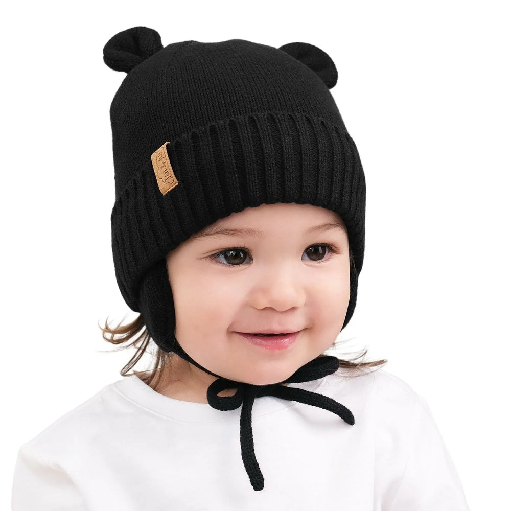 Jan & Jul Kids Bear Knit Hats Jet Black worn by a smiling toddler with bear ears and tied chin strap.
