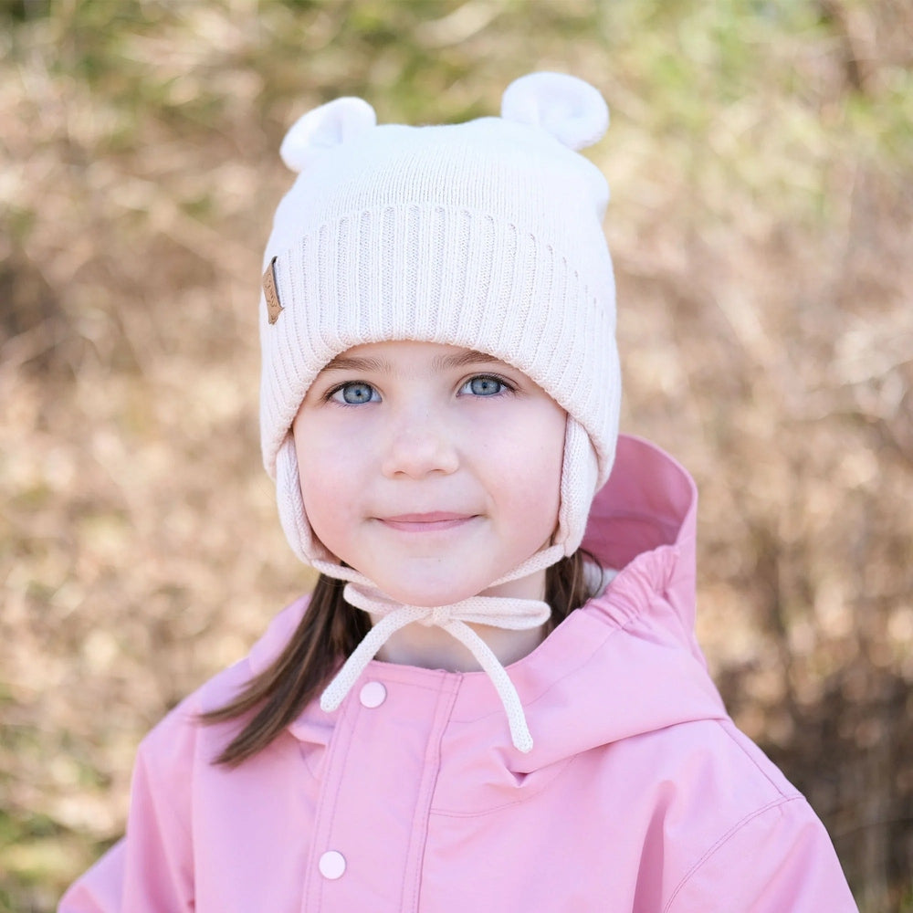 JAN & JUL kids bear knit hat in light pink with bear ears on a smiling toddler.