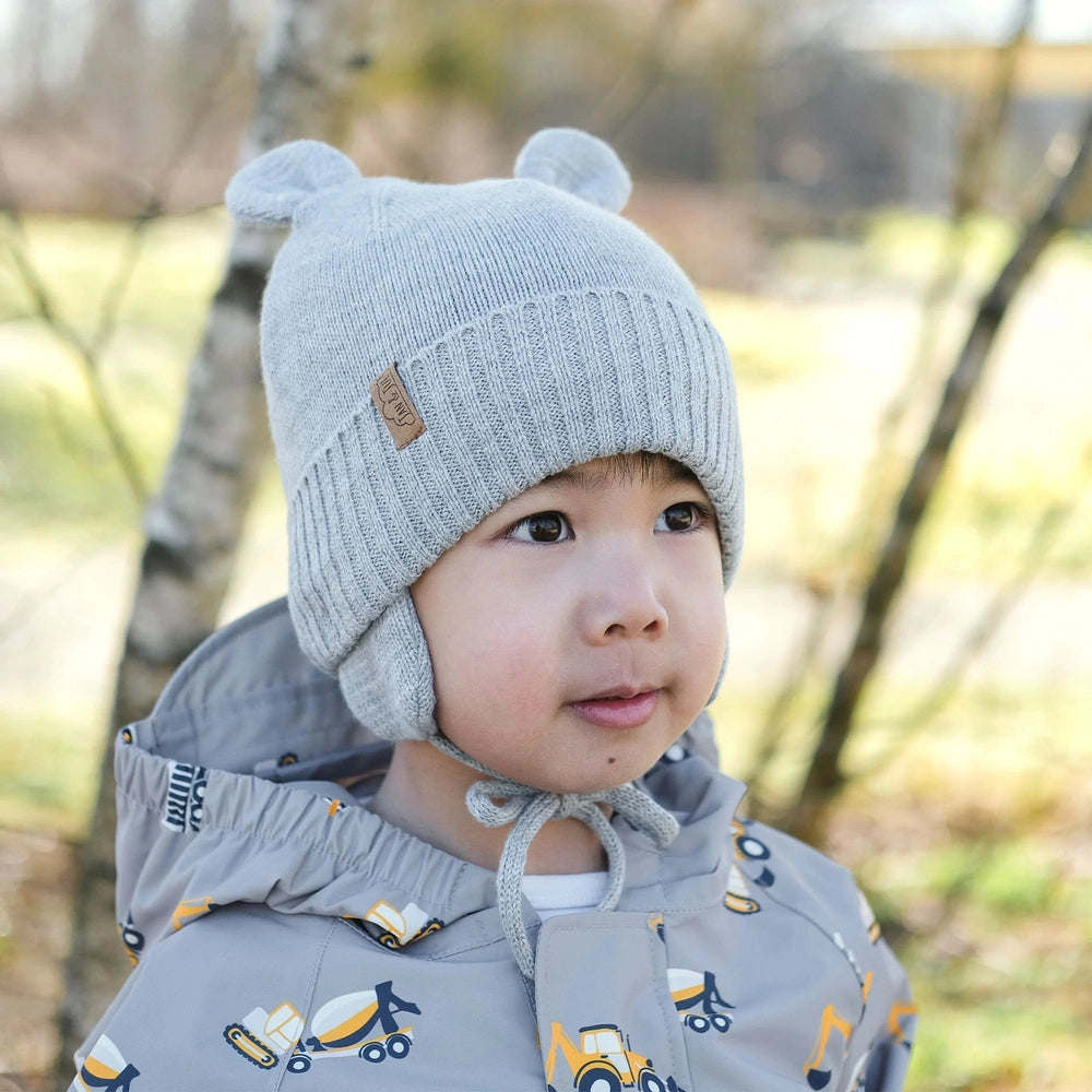 JAN & JUL Kids Bear Knit Hat in soft grey worn by a toddler outdoors; ribbed knit with bear ears and chin ties