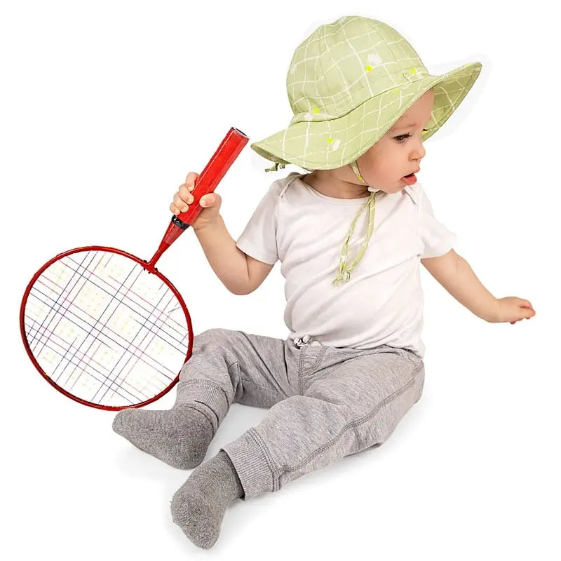 Jan & Jul Kids Cotton Floppy Hat Birdie, light green grid-pattern with chin tie on a toddler reaching for a red racket.