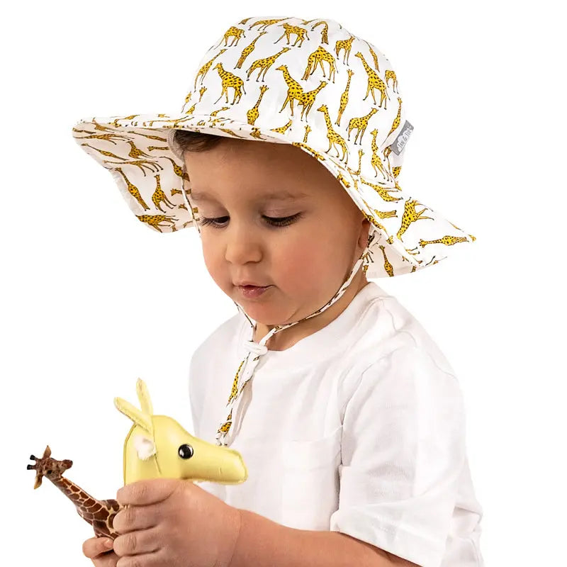 JAN & JUL Kids Cotton Floppy Hat Giraffe print with a wide brim and chin strap worn by a toddler.